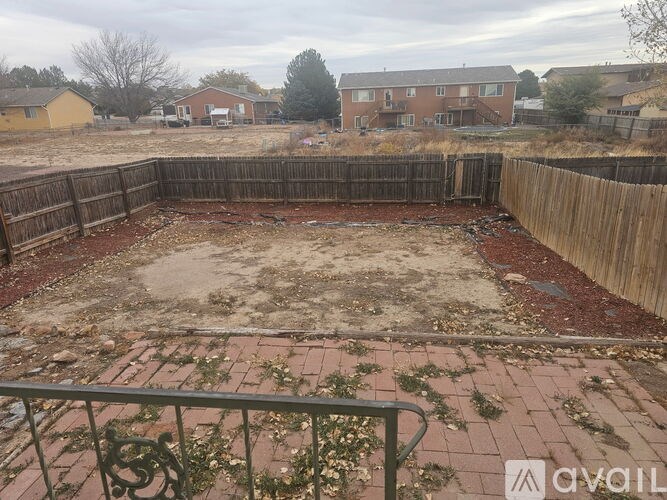 A backyard with a wooden fence and a brick patio.