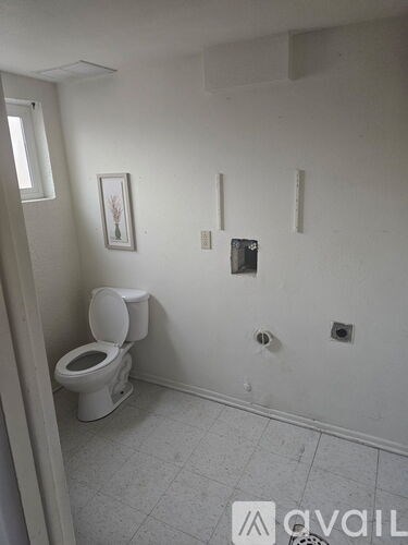 A white toilet in a small bathroom with a picture on the wall.