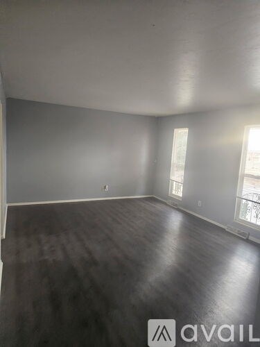 A room with grey walls and wooden flooring is available for rent.