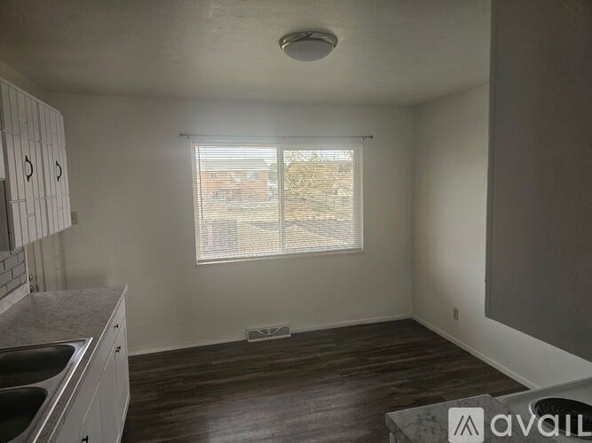A kitchen with a window and wooden floors.