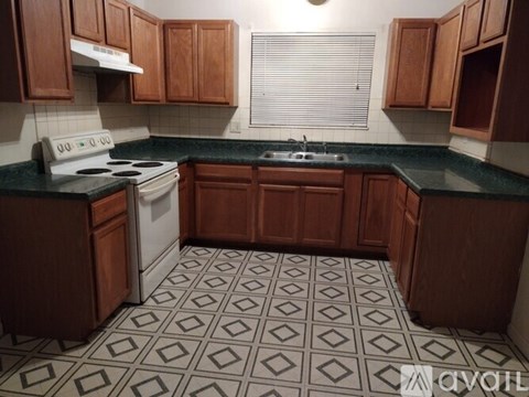 A kitchen with a white stove top oven and a black and white tiled floor.