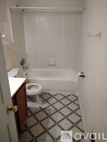A white bathroom with a toilet, tub, and tiled floor.