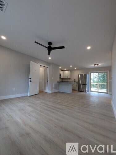 A spacious room with a ceiling fan and wooden flooring.