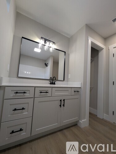 A bathroom with a mirror, sink, and cabinets.