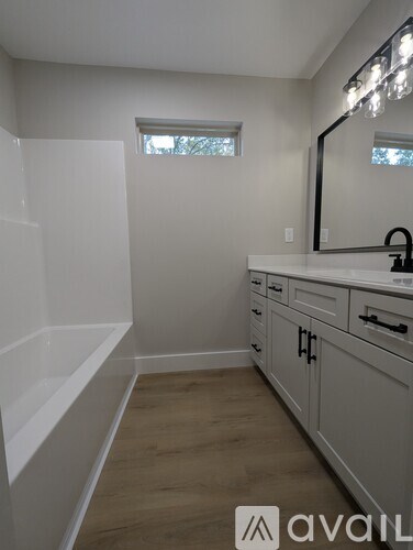 A bathroom with a white tub and a window.