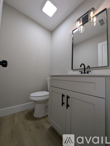 A bathroom with a toilet, sink, and mirror.