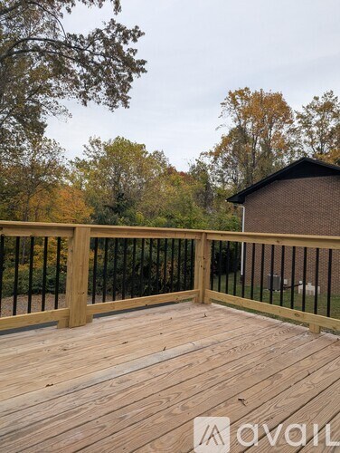 A wooden deck with a railing and a building in the background.