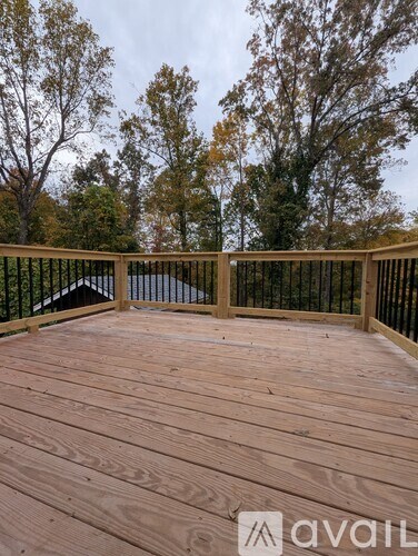 A wooden deck with a black railing and trees in the background.