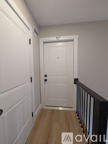 A hallway with a door numbered 102 and a balcony with a black railing.