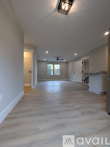 A spacious room with wooden flooring and a ceiling fan.