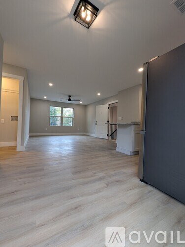 A spacious room with wooden flooring and a ceiling fan.