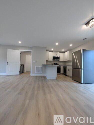 A spacious kitchen and living room with wooden flooring and modern appliances.