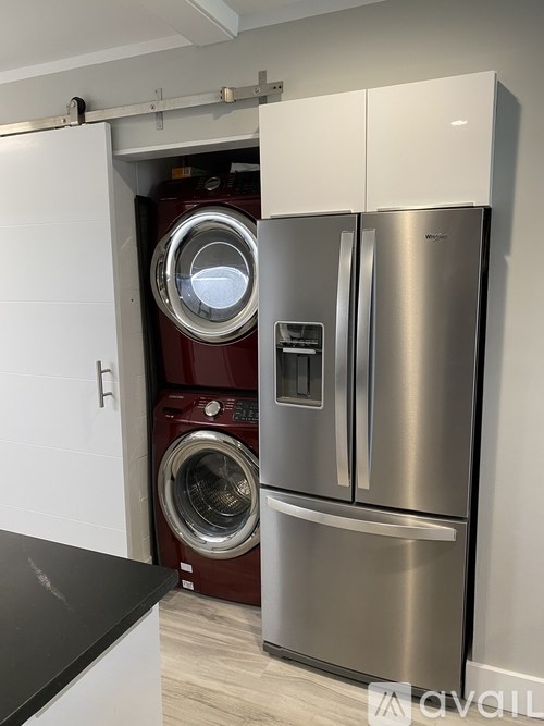 A stainless steel refrigerator and washing machine in a laundry room.