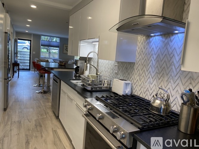 A modern kitchen with a black stove top and wooden floors.