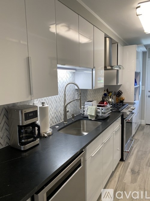 A kitchen with a black countertop and white cabinets.