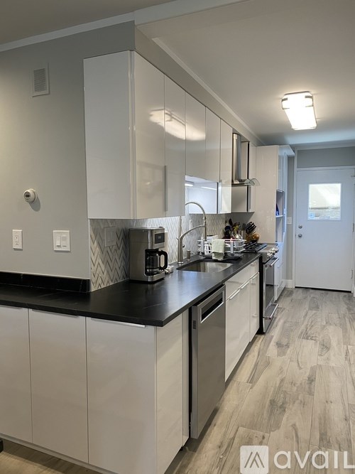 A kitchen with white cabinets and a black counter top.