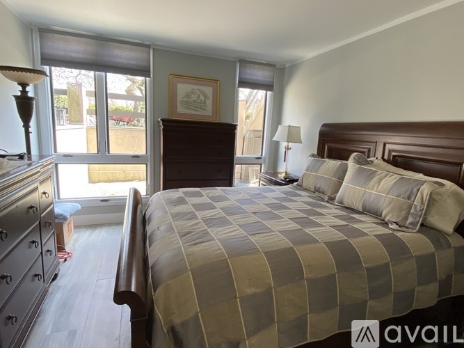 A bedroom with a bed, dresser, and window with blinds.
