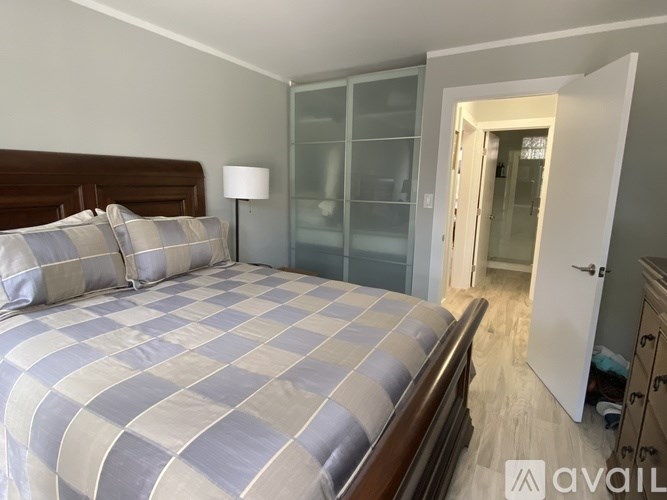 A bedroom with a bed, nightstand, and a doorway leading to another room.