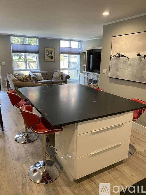 A modern kitchen with a black countertop and red barstools.