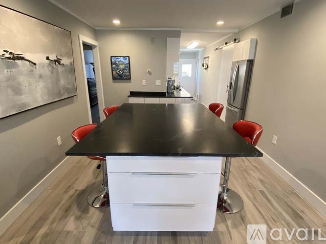 A black table with red chairs and a white drawer unit in front of it.