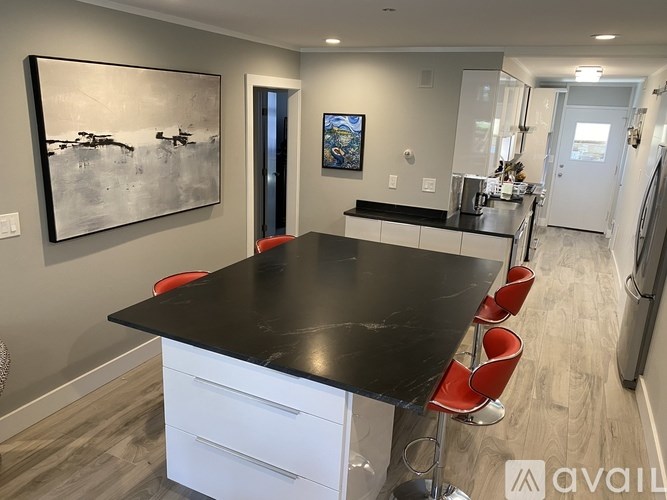 A black table with red chairs in a modern kitchen.