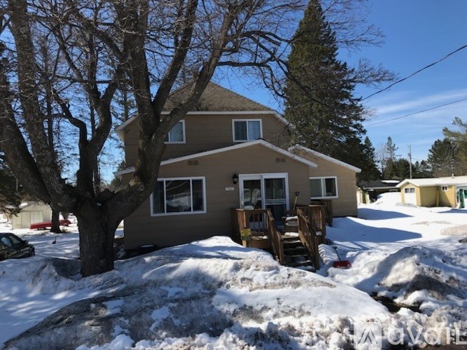 A house with a brown roof and a tree in front of it.