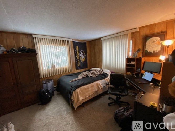 A room with a bed, desk, and chair.