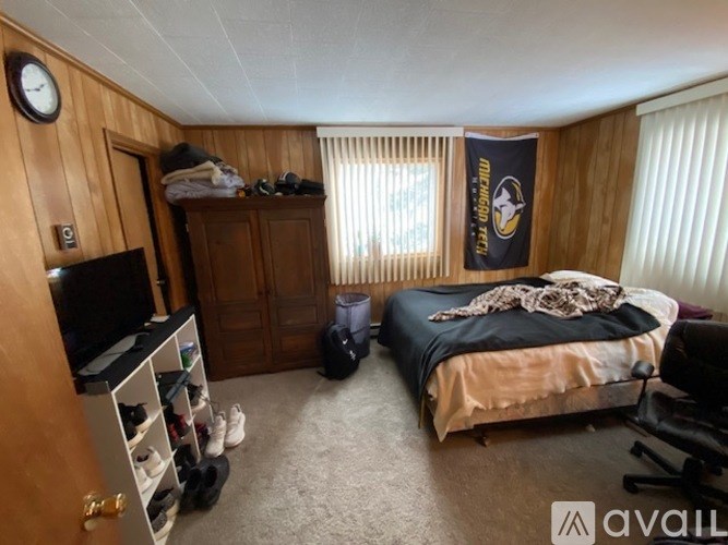 A bedroom with a bed, a TV, a wardrobe, and a clock on the wall.
