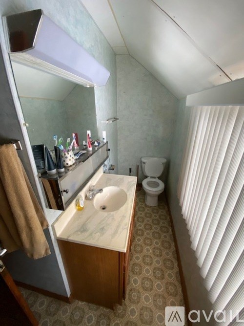 A bathroom with a toilet, sink, and mirror.