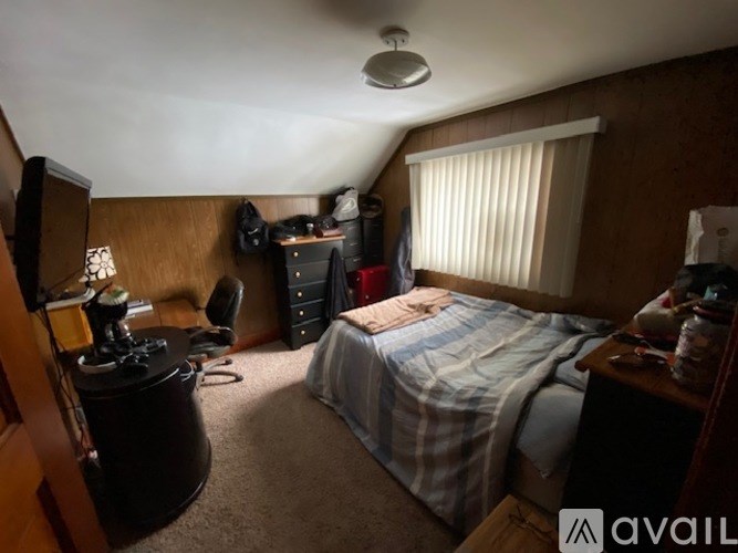 A bedroom with a bed, dresser, and window with blinds.