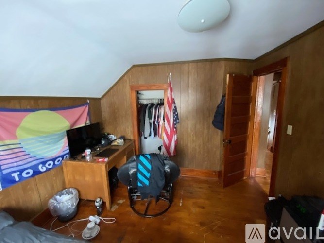 A room with a bed, a desk with a computer, and a flag hanging on the wall.