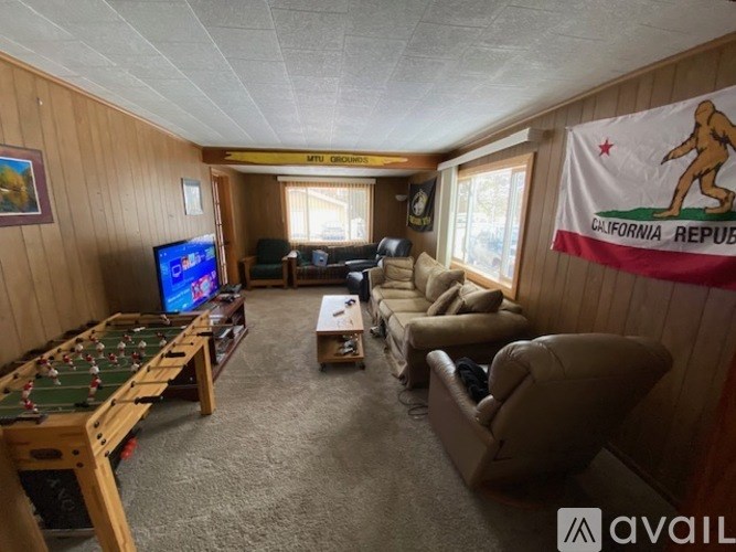 A room with a foosball table, couches, and a TV.