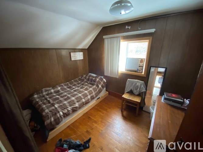 A room with a bed, a chair, and a window.