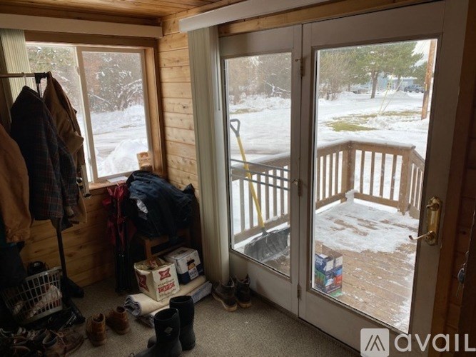 A view of a snowy landscape from a room with a cluttered floor.