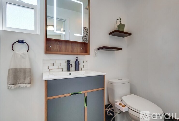 A bathroom with a toilet, sink, mirror, and towel rack.