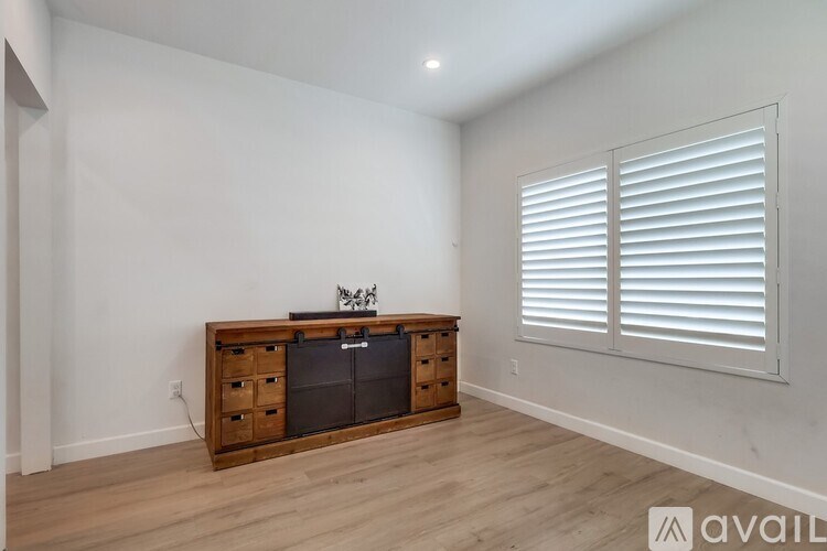 A room with a wooden cabinet and a flat screen TV on top of it.