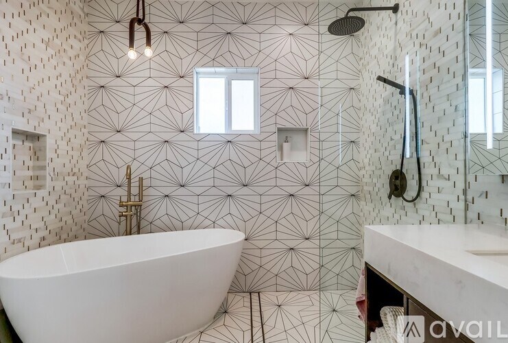 A white bathtub sits in a bathroom with a wallpapered wall and a window.