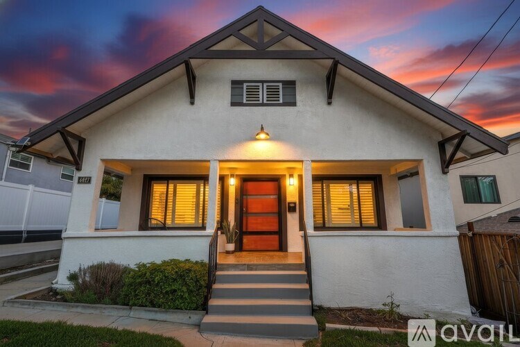 A house with a brown door and windows is shown with a sunset in the background.