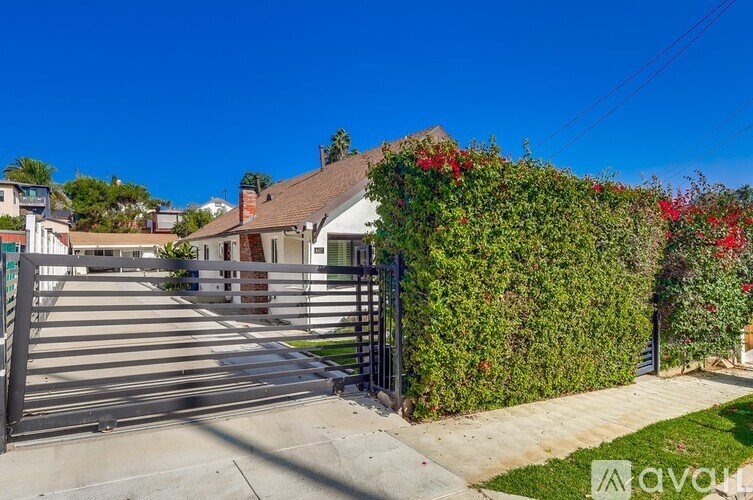 A house with a green hedge and red flowers in front.