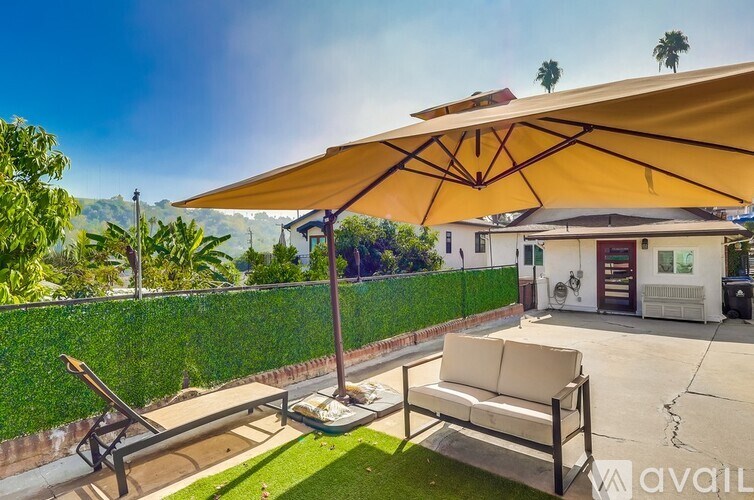 A patio with a couch and a table under a yellow umbrella.