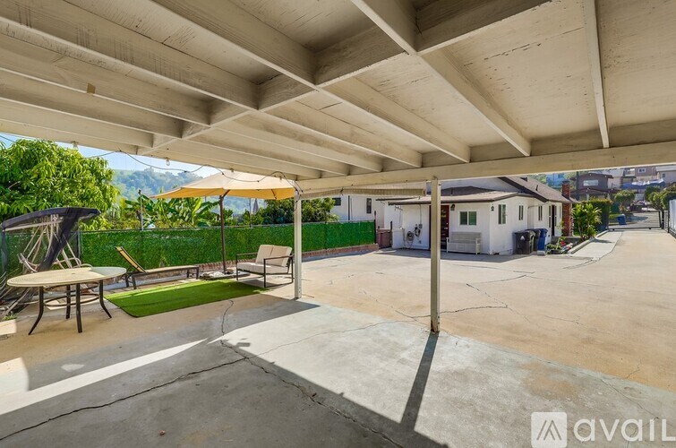 A patio area with a table and chairs under a roof.