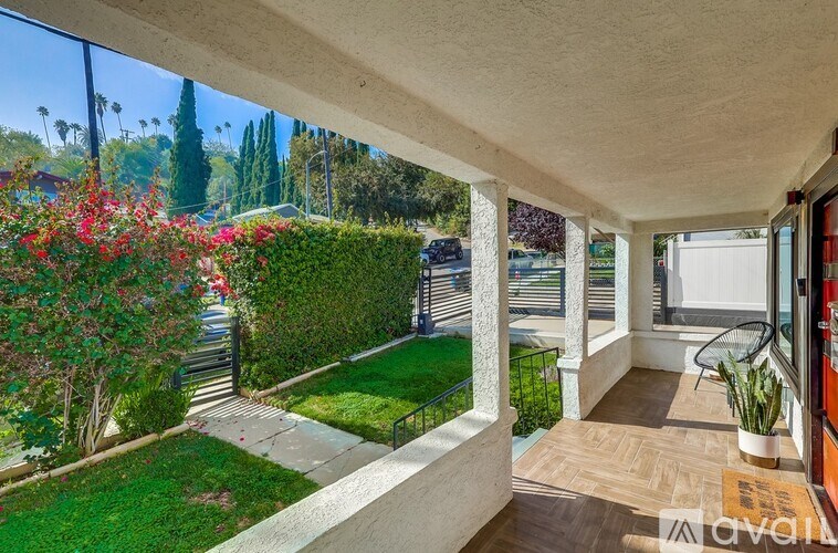 A balcony with a view of a green lawn and trees.
