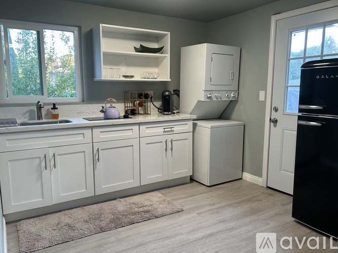 A kitchen with white cabinets and a black fridge.