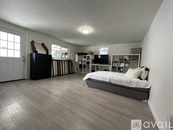 A bedroom with a bed, dresser, and shelves.