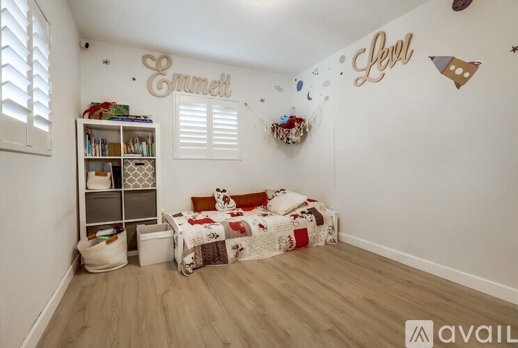 A room with a bed and a bookshelf with the word "Emmett" written on the wall.