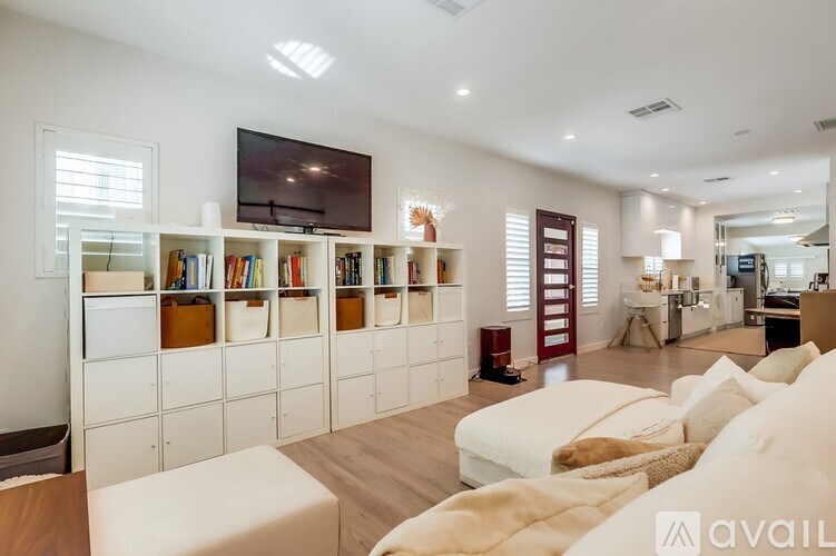 A living room with a white couch, a television, and a bookshelf.