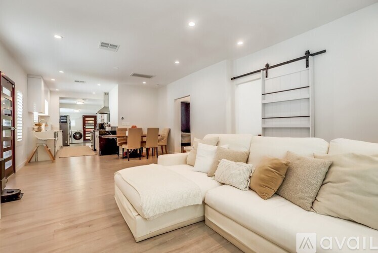 A spacious living room with a white sofa and wooden flooring.