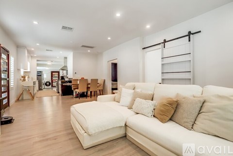 A spacious living room with a white sofa and wooden flooring.