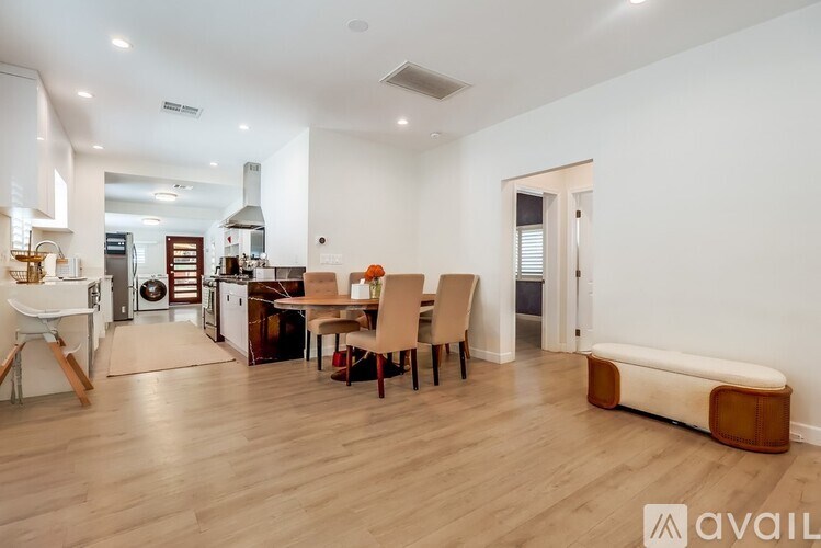 A spacious living room with a dining area and a kitchen in the background.