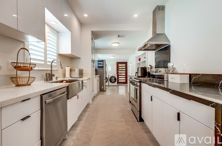 A modern kitchen with white cabinets and stainless steel appliances.